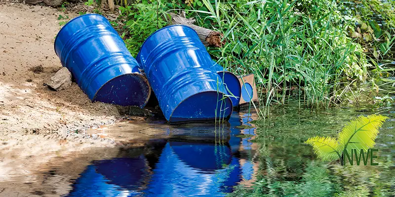 Three blue metal oil drums staged outdoors, awaiting hazardous waste disposal by NWE Waste Services Ltd in Lancashire.