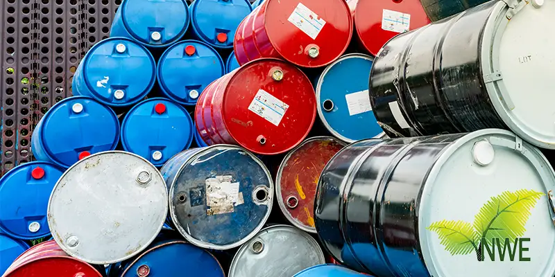 Oil drums stacked on pallets outdoors, prepared for safe hazardous waste disposal at a university in Northern England.